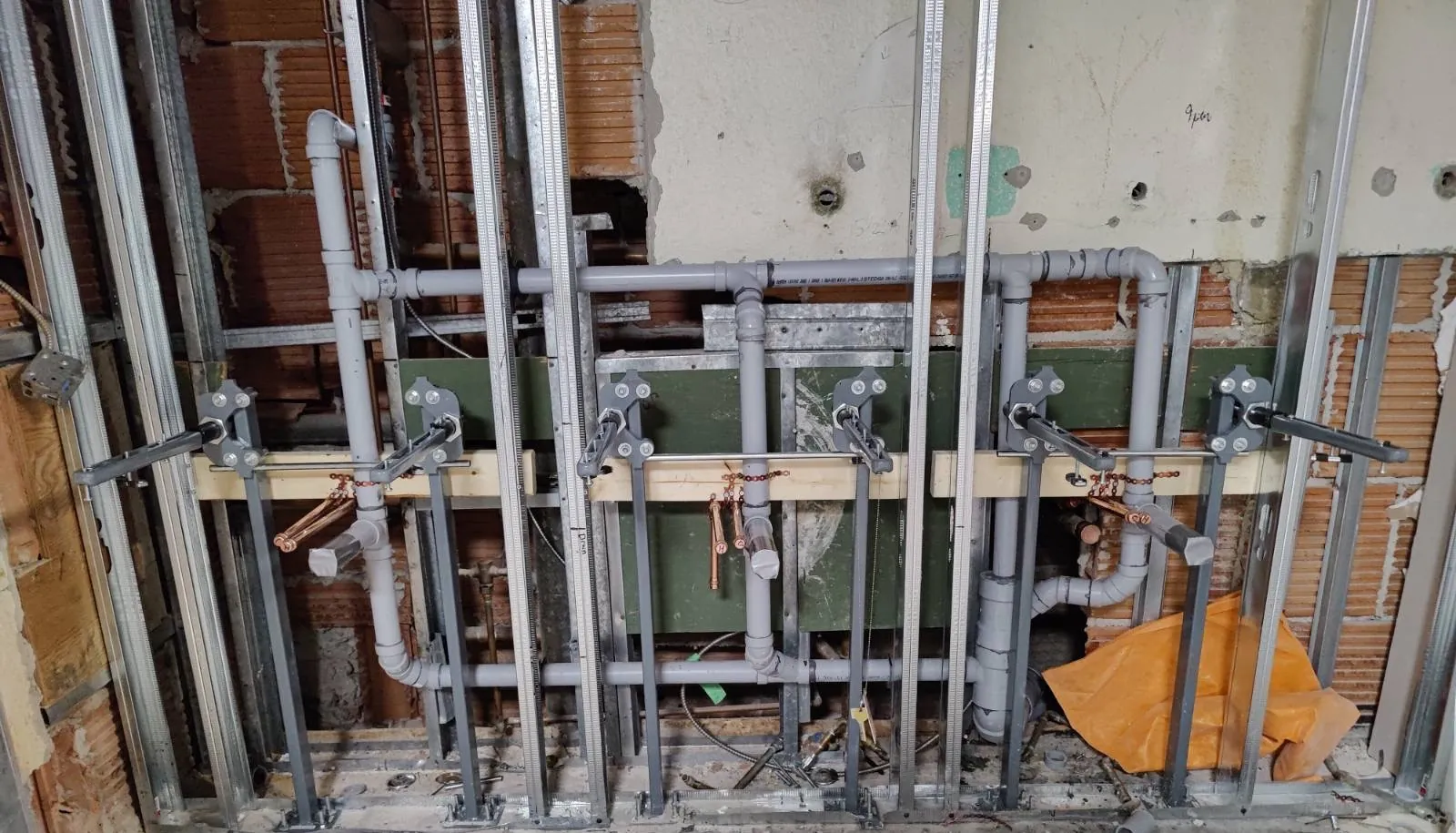 Plomberie brute en cours d'installation dans un mur à colombages métalliques